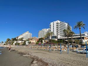 贝纳尔马德纳Benalmadena Playa的一个带躺椅和建筑的海滩和一个城市