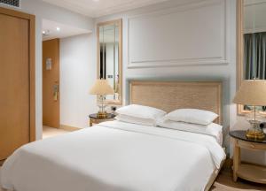 麦纳麦Palmyard Hotel的卧室配有一张白色大床和两盏灯。