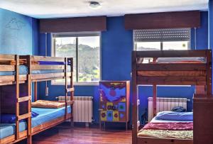 圣地亚哥－德孔波斯特拉Meiga Backpackers Hostel的蓝色墙壁的客房内设有两张双层床。