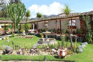 Los Baños del IncaHOTEL & SPA LAGUNA SECA的一座花园,位于一座带喷泉的房屋前