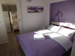 滨海圣芒德里耶Bas de villa jardin plein sud proche mer clim-Wifi的一间卧室配有一张大床和紫色毯子