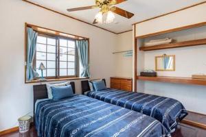 读谷村Beach House Yomitan的一间卧室配有两张床和吊扇
