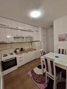 波德戈里察Your place in Podgorica的厨房配有白色橱柜和桌椅