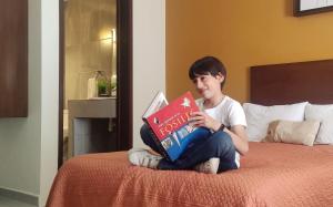 阿瓜斯卡连特斯Posada Del Carmen Aguascalientes的坐在床上看书的男孩