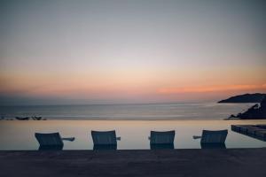塔马林多塔马林多温德姆酒店的日落时分带椅子的游泳池和海洋