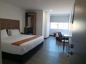 波哥大HOTEL AMERICAN VISA CORPORATE的酒店客房配有一张床和一张带椅子的书桌