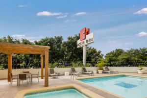 瓜达拉哈拉瓜达拉哈拉博览会嘉年华酒店的游泳池,带泳池旅馆标志和椅子的酒店