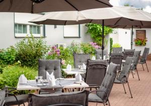 拉姆斯泰因-米森巴赫Hotel Rosenhof GmbH的室外餐厅设有桌椅和遮阳伞。