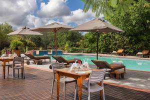 马翁Sedia Riverside Hotel的游泳池旁带桌子和遮阳伞的天井