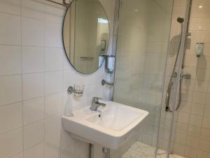 斯海弗宁恩Fisherman's House by Hofstad Hotels的浴室配有盥洗盆和带镜子的淋浴