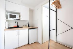 土伦Ode à l'amour : studio intimiste的厨房配有白色橱柜和微波炉