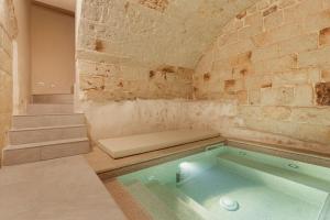 法萨诺[Exclusive - Suite] SPA con Idromassaggio Jacuzzi的砖墙房间内的热水浴缸