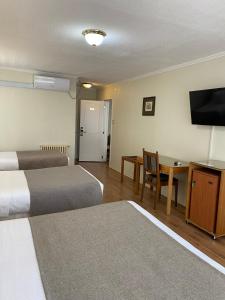 瓦尔迪维亚Hotel Melillanca的酒店客房设有两张床、一张桌子和电视。