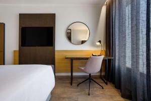 塔那那利佛Radisson Blu Hotel Antananarivo Waterfront的一间卧室配有一张床、一张书桌和一面镜子