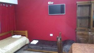 奥拉瓦里亚Mi Lugar的红色的房间,设有两张床和墙上的电视