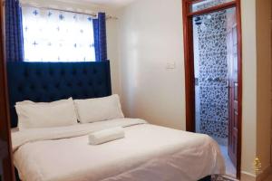 内罗毕Neema Court Jamhuri-woodly的一间卧室配有一张带蓝色床头板的床和窗户