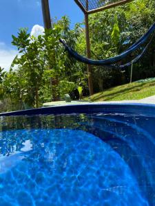 巴西利亚Sunshine Chalé Brasília-DF的庭院内带吊床的蓝色游泳池