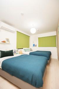 大阪鶴橋駅までただ五分間の好立地的卧室设有两张绿色和白色的床