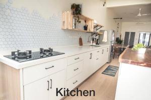 巴特沃思M12 Homestay, Butterworth的厨房配有白色橱柜和炉灶。