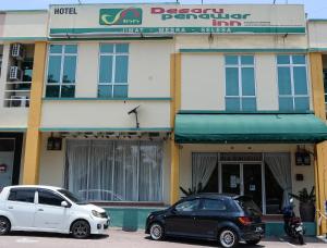 迪沙鲁Desaru Penawar Inn的两辆汽车停在大楼前