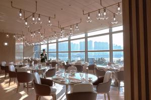 香港荃湾西如⼼酒店的一间设有桌椅的餐厅,以及一位背景人士