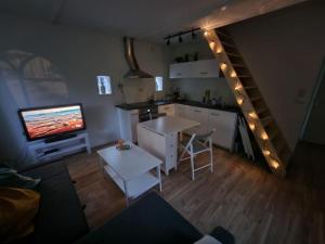 彼得比伦Huisje in Pieterburen的一间带厨房、电视和楼梯的客厅
