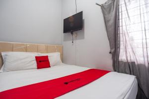 Kemirimuka DuaRedDoorz near Margonda Raya的卧室配有红色毯子,位于床上