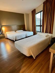 拉古纳德杜埃罗Hotel Duero的酒店客房设有两张床和窗户。
