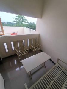 井里汶Anugrah homestay的一间设有三把椅子、一张长凳和窗户的房间