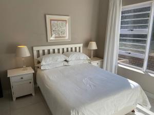 阿尔弗雷德港Loerie Nest的卧室配有白色床、两个床头柜和窗户。