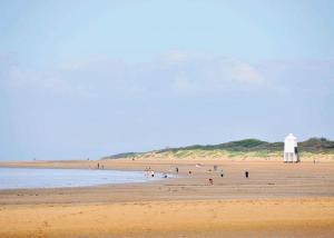 伯翰姆昂斯Lakeside Holiday Park的一群人在海滩上,有一座灯塔