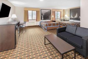 利格城Super 8 by Wyndham League City Kemah Area的酒店客房设有沙发、床和电视。