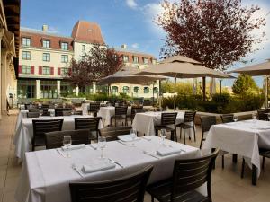 马尼库尔勒翁格尔巴黎迪森蓝光酒店 - 马恩拉瓦莱的一间设有白色桌椅和遮阳伞的餐厅