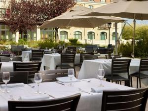 马尼库尔勒翁格尔巴黎迪森蓝光酒店 - 马恩拉瓦莱的一间设有白色桌椅和遮阳伞的餐厅