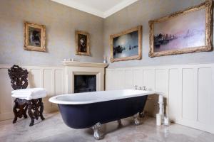 柯比朗斯代尔The Casterton Grange Estate的大型浴室设有大浴缸和绘画作品。