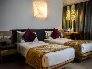 科泽科德Nexstay Asma Tower的酒店客房设有两张床和一张桌子。