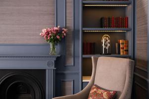 伦敦托普汉姆斯酒店的一间设有壁炉和带花瓶的椅子的房间