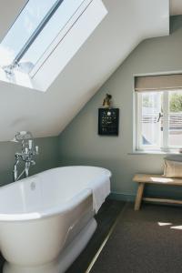 HarpsdenThe Bottle & Glass Inn的浴室配有白色浴缸,设有天窗
