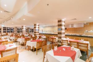 艾因苏赫纳Coral Sea Beach and Aqua Park的餐厅设有红色和白色的桌椅