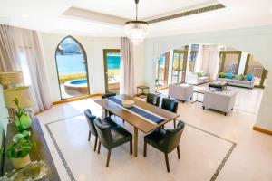 迪拜FAM Living - Palm Jumeirah - Beach Villas with Private Pool的一间带桌椅的用餐室和一间客厅