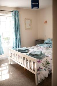 萨弗伦沃尔登Braybrooke Cottage, Saffron Walden的一间卧室配有一张带蓝色窗帘的床和一扇窗户