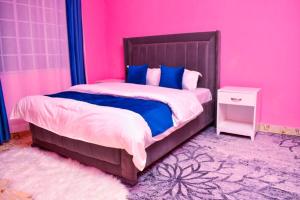 基苏木Lux Suites 1 Bedroom Okore Estate Apartment Kisumu的粉红色的卧室,配有一张床和粉红色的墙壁
