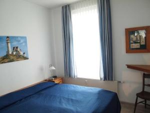奥斯赛拜-屈隆斯博恩Parkblick - 01-09的一间卧室配有一张蓝色的床和一个带灯塔的窗户。
