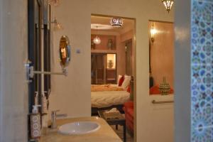 瓦尔扎扎特Riad Tama & spa的一间带水槽的浴室和一间带床的房间