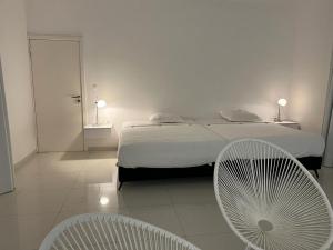 索蒙Villa Carabane的一间卧室配有一张床和两把白色椅子