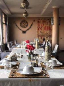 瓦尔扎扎特Riad Tama & spa的一张长桌子,上面有白色的板子和红色的花
