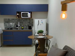 特雷斯拉瓜斯Studio Standard Comfort I AO LADO SHOPPING的厨房配有蓝色橱柜、桌子和冰箱。