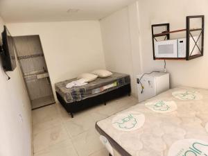 里约达欧特拉斯POUSADA FLOR DO CARIBE的小房间设有两张床和微波炉