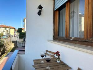 比萨Appartamento VN House的阳台上的长凳上放两杯葡萄酒