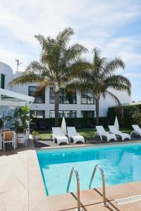 厄尔·波普瑙·德尔·戴尔三角洲拉尔加迪尔酒店的一个带白色躺椅的游泳池,棕榈树